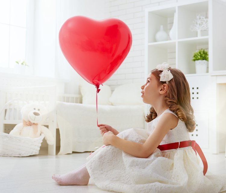 Young girl holding a red heart balloon